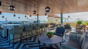 A rooftop bar with a wooden ceiling, hanging spherical lights, and a view of the ocean. - 1BR Condo Best Location (Playa del Carmen)