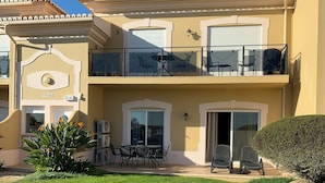 A two-story building with a balcony, outdoor seating, and a paved driveway.