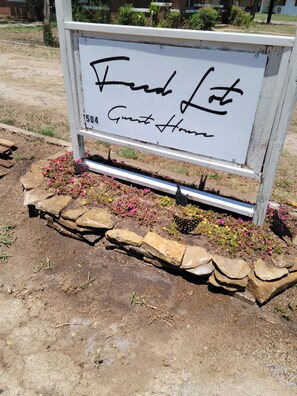 A sign for 'Fred Lot Guest House' with a number '504' and a garden area with flowers and rocks.