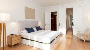 A modern bedroom with a large bed, bedside tables, a wardrobe, and a chair.