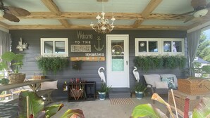 A covered porch with a wooden ceiling, a welcome sign, potted plants, and outdoor seating. - Cedar Point, Sports Force, Kalahari Near Cottage. Boat Parking ez Walk to Beach! (Huron)
