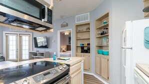 A modern kitchen with a built-in stove, microwave, and refrigerator. There are wooden cabinets and a countertop with various kitchen items. - Inviting Coastal Stay Near Beach With Pool, Hot Tub, and Private Balcony (Corpus Christi)
