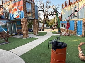 A building with a 'Gulf' sign, outdoor seating, a pathway, and a statue.