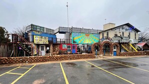 Un estacionamiento con un edificio que presenta un mural colorido y un letrero que dice "Great Ash Cans".