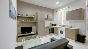 A modern kitchen with a built-in oven, microwave, and sink. There is a dining area with a glass table and a bench.