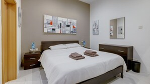 A modern bedroom with a large bed, a wooden nightstand, a dresser, and abstract artwork on the walls.