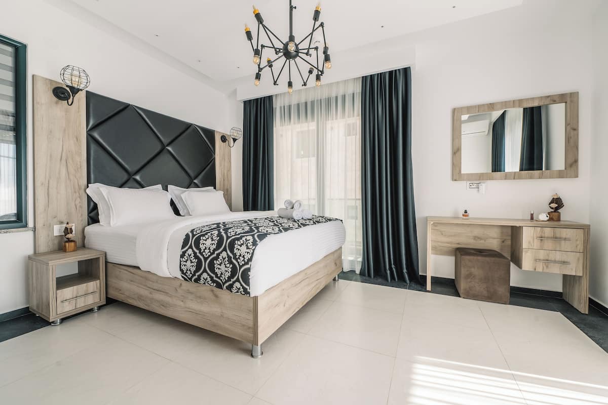 Un dormitorio moderno con cama, mesitas de noche, escritorio y espejo.