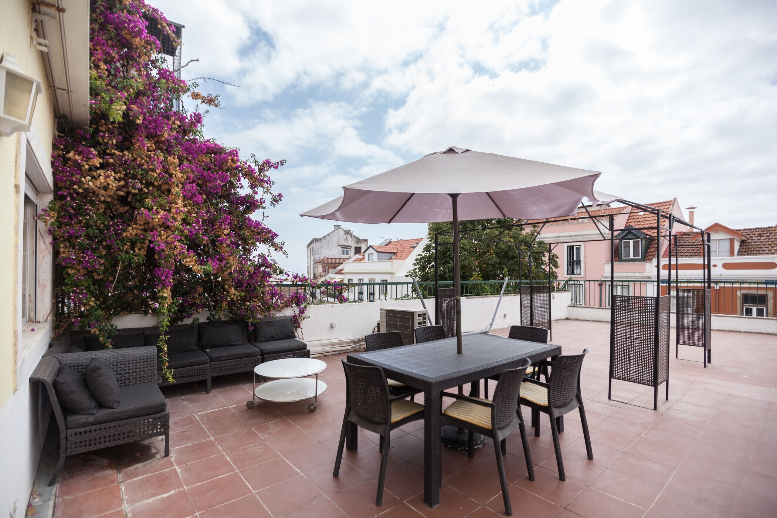 An outdoor patio with a table and chairs, a sofa, and a large umbrella.