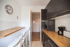 A modern kitchen with wooden countertops, a stainless steel oven, and a coffee maker.