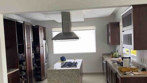 Cocina con una isla central, armarios de madera, una ventana y una campana extractora de acero inoxidable.
