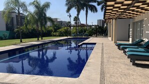 Una piscina con sillas de descanso y palmeras.