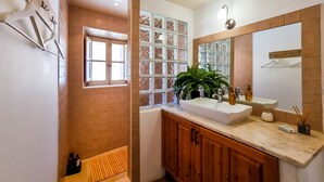 Une salle de bain avec un meuble-lavabo en bois, un grand miroir et une fenêtre dotée de panneaux en verre dépoli.