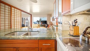 Una cocina con armarios de madera, encimera de granito, un lavamanos y un hervidor.