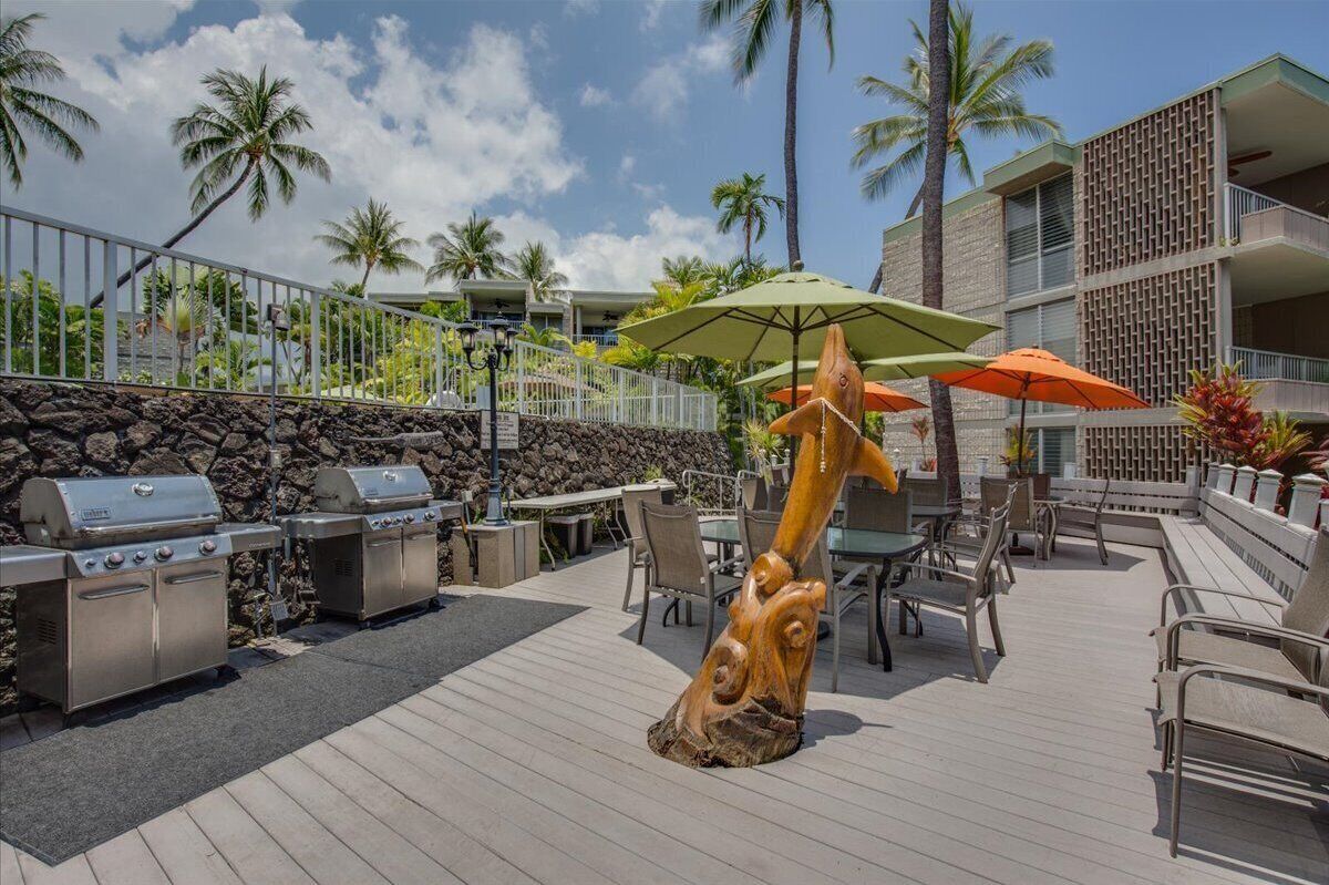 An outdoor patio with grilling stations, seating, and a decorative wooden sculpture.