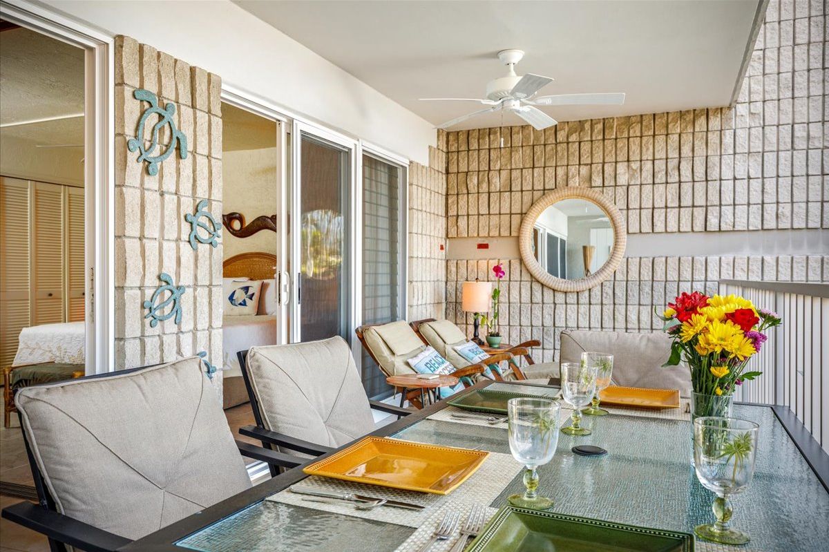 A dining area with a glass table, chairs, and a ceiling fan.