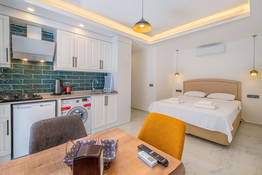 A compact hotel room with a kitchenette, a bed, and a dining area.