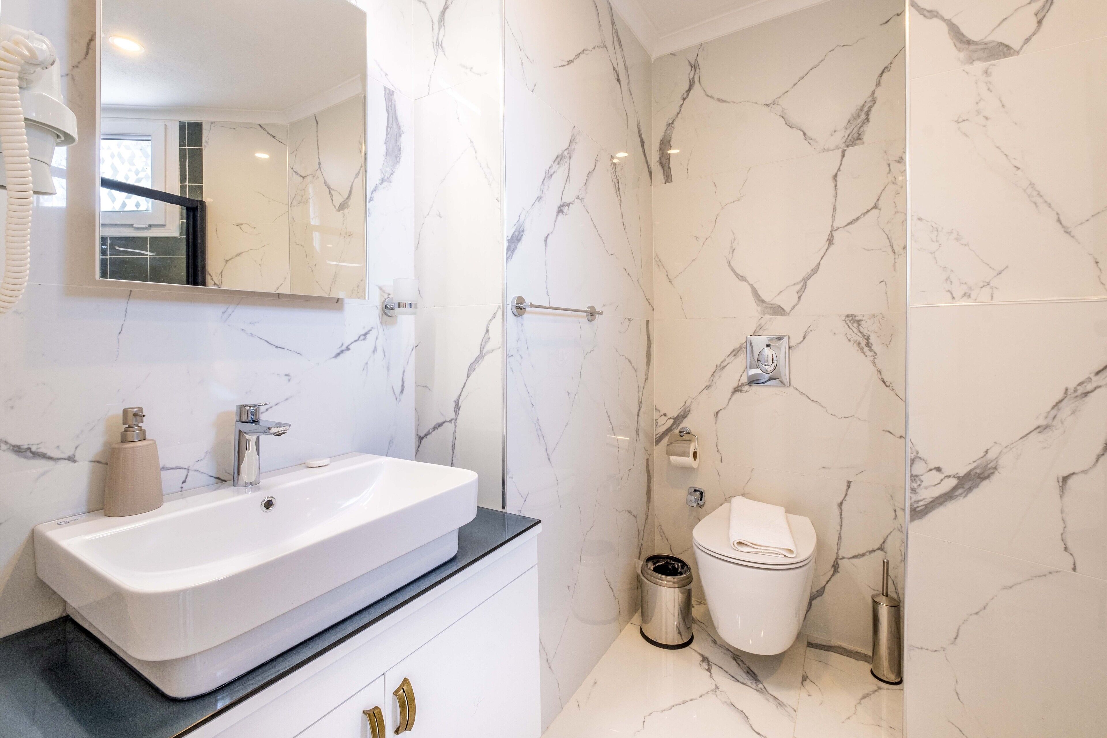 A modern bathroom with a large white sink, a mirror, and a toilet.