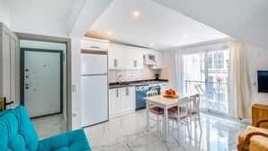 Una cocina moderna con armarios blancos, un comedor con mesa y sillas, y un amplio ventanal con vistas al exterior.