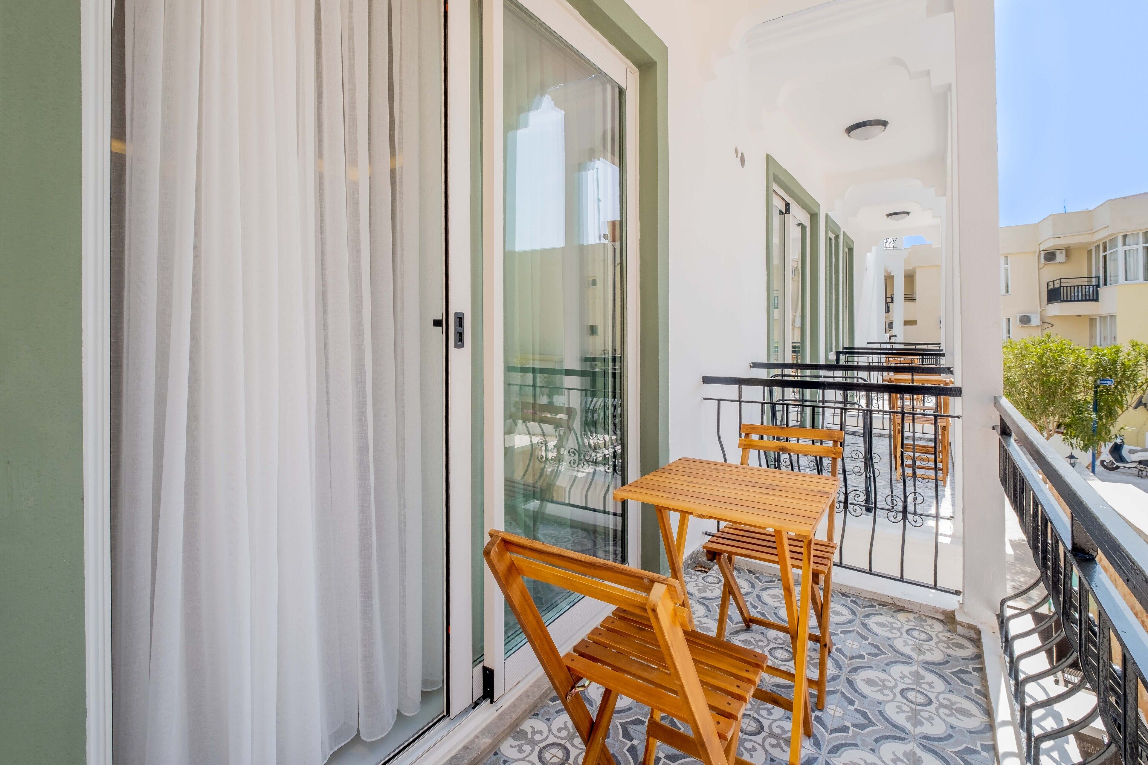 A balcony with a glass door, a wooden table, and chairs.
