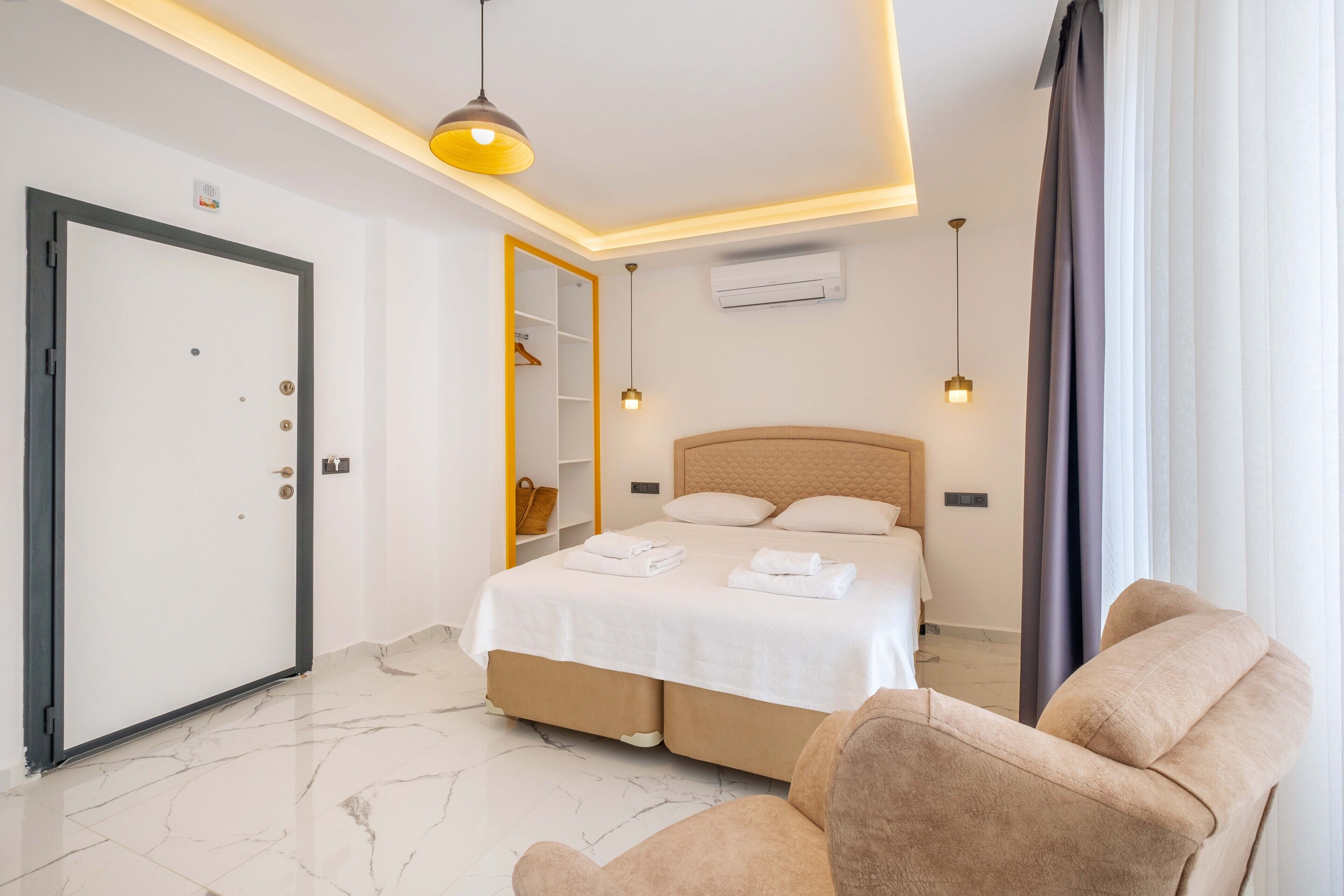 Una habitación de hotel con cama, una silla, un armario y una puerta.