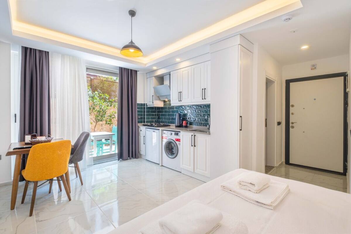 Quarto de hotel moderno com área de refeições, cozinha compacta e vista para o exterior.