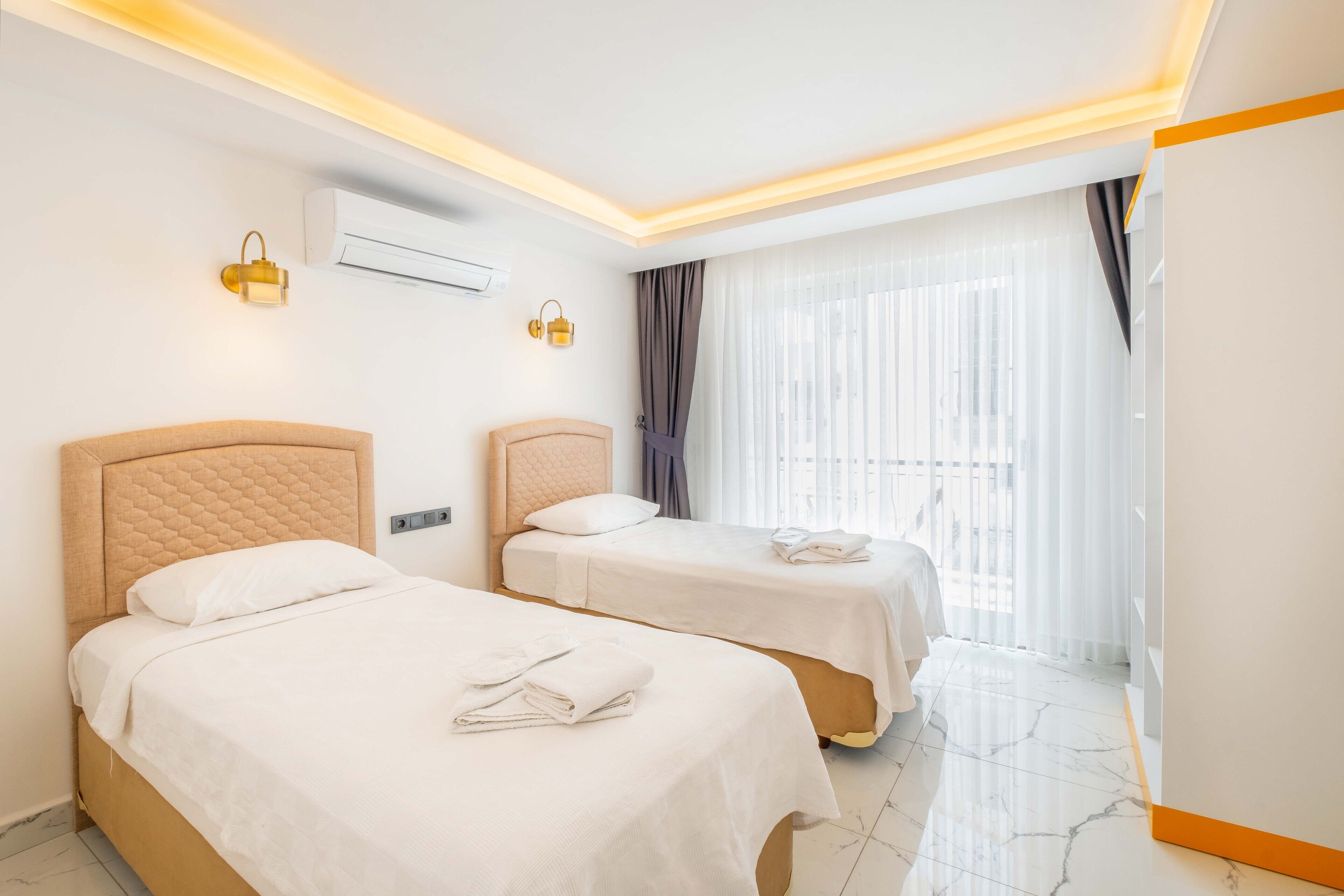 Une chambre d’hôtel avec deux lits, une grande fenêtre avec des rideaux et un design moderne au niveau du plafond.