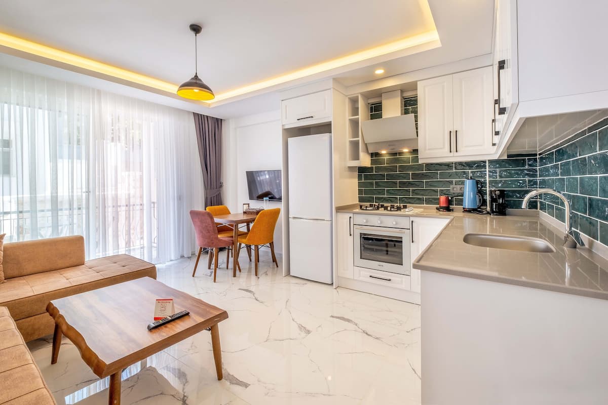 Cozinha moderna com armários brancos, bancada de mármore e forno embutido.