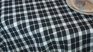 Une table à manger recouverte d’une nappe à carreaux, avec des assiettes et une bouteille de vin.