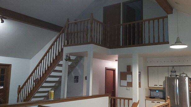 Un intérieur de maison à plusieurs niveaux comprenant un escalier, un espace cuisine et un coin repas.