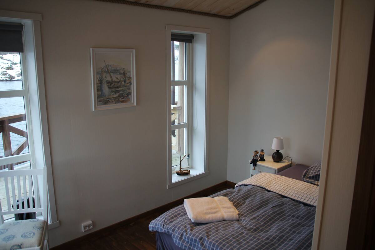 A bedroom with a bed, a window, a nightstand, and a chair.