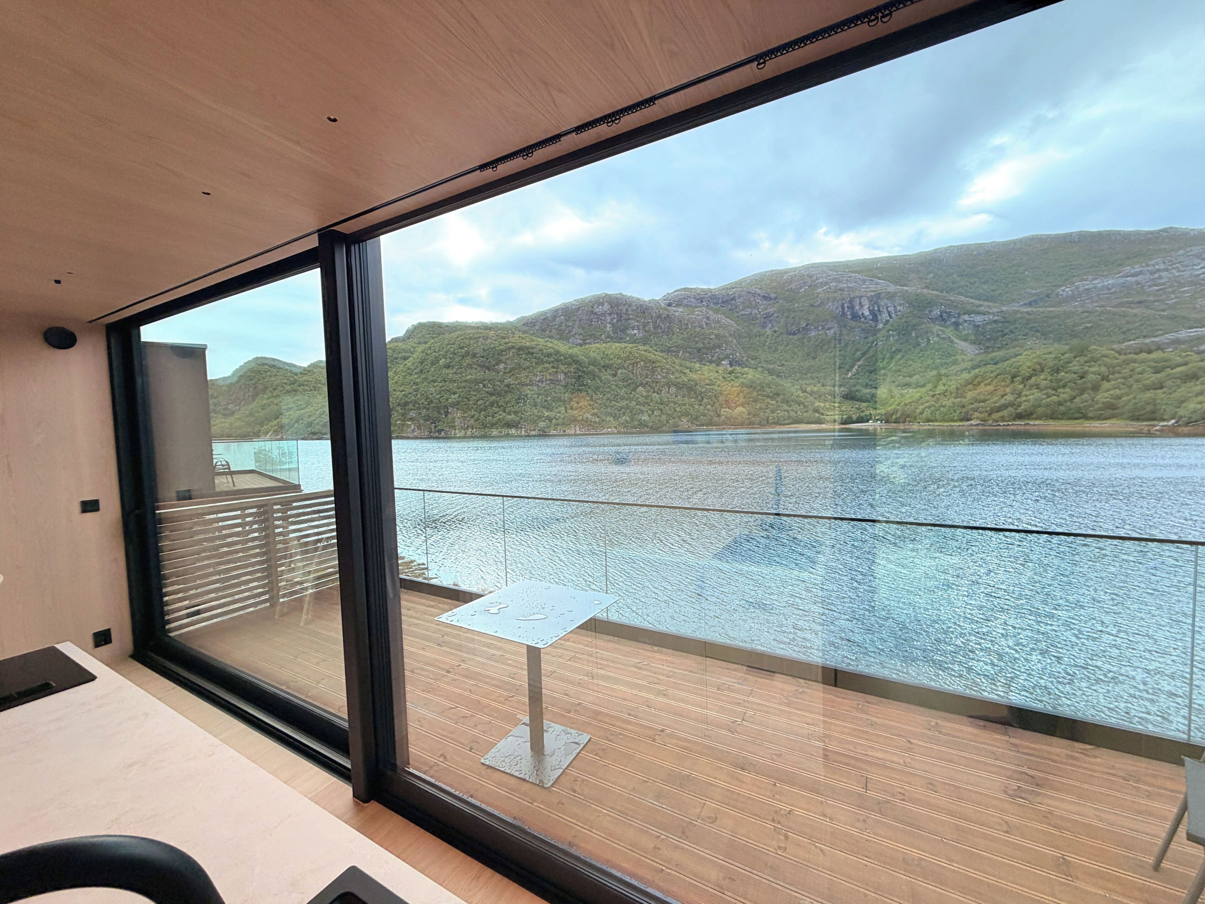 Una habitación con un ventanal grande que da a un lago y montañas.