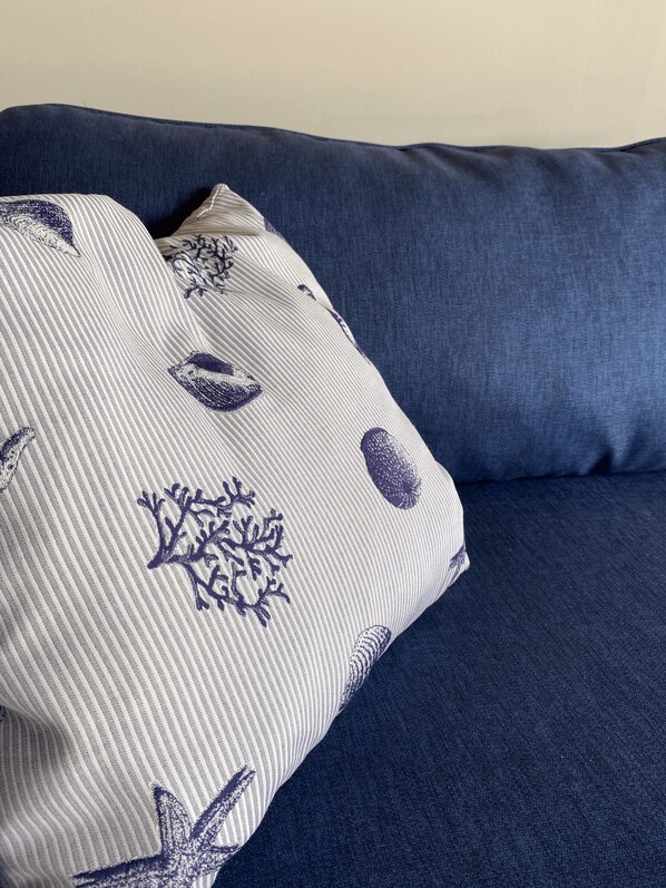 A blue sofa with a patterned pillow.