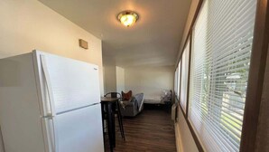 A narrow hallway with a white refrigerator, a small table, and a couch in the background. - Liberty Valley Studios in Madison, Wi! (Madison)