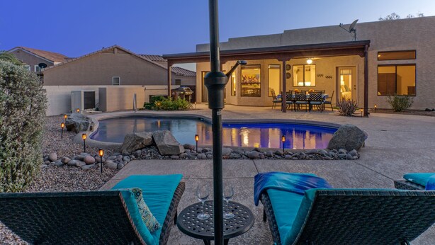 Un giardino con piscina, poltrona da relax e zona patio.