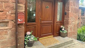 Een stenen gebouw met een houten dubbele deur, nummer 12, en een brievenbus.