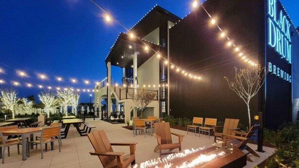 An outdoor seating area with tables and chairs, a fire feature, and a building with 'BLACK DRUM BREWING' signage. - Beautiful 2 BedroomVilla in Kingston Resort (North Myrtle Beach)