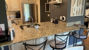 A kitchen with granite countertops, stainless steel appliances, and bar stools. - Beautiful 2 BedroomVilla in Kingston Resort (North Myrtle Beach)