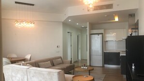 A modern living room with a sofa, two small wooden tables, and a chandelier. - Mall Of İstanbul Residence (Istanbul)