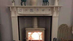 A cozy room with a white fireplace, a rug, and a basket of items. - Holmlea Cottage, a sweet and charming getaway in a picturesque Fife village. (Freuchie, Fife)