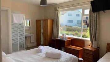 Habitación de hotel con cama, escritorio, armario y ventana con vista a edificios.