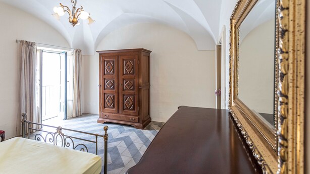 Une chambre à coucher avec un lit, une commode, un miroir et un lustre.