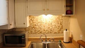 A kitchen with a microwave, double sink, and a decorative stone wall. - Red Bank Cozy Nest! (Chattanooga)