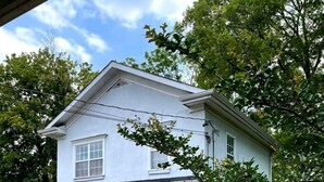 A two-story house with a red door, stone foundation, and a small porch with red Adirondack chairs. - Red Bank Cozy Nest! (Chattanooga)