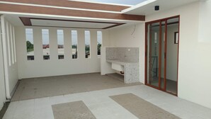 A modern interior with a tiled floor, a built-in kitchen counter, and a sliding glass door leading to an outdoor area.