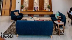 Un salon moderne avec un canapé bleu, un mur d’accent en bois et des luminaires suspendus.