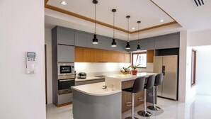 Une cuisine moderne dotée d’un îlot central, de tabourets de bar et de luminaires suspendus.