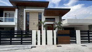 Une maison moderne à deux étages, dotée d’un balcon, d’une entrée sécurisée par un portail et d’une allée.