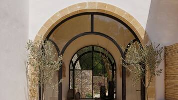 Un ingresso ad arco con piante in vaso, una panchina di legno e un muro in pietra.
