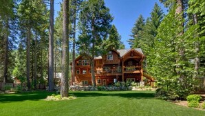 A large, multi-story log cabin with a spacious front porch and a well-maintained lawn. - Lazy Bear Lodge in Homewood - hot tub, close to lake, large home (Homewood)