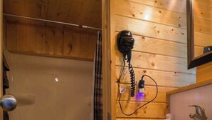 Ein Badezimmer einer Holzhütte mit Dusche, Toilette und Waschbecken.